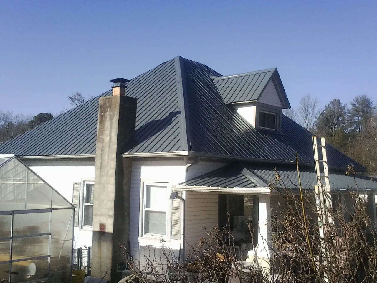 Dark blue standing seam metal roof on a white farmhouse with dormer — Slate & Tile Roof Repair by Roofing Brothers in Cochecton