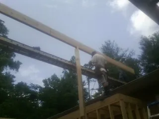 Carpenter setting a ridge beam over a new addition frame — Ice Dam Removal by Roofing Brothers in Cochecton