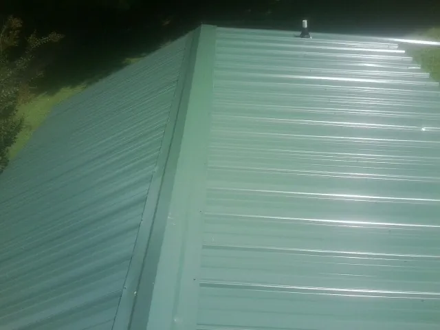 New green metal panels meeting at the ridge of a roof — Flat Roof Repair work by our crew in Cochecton