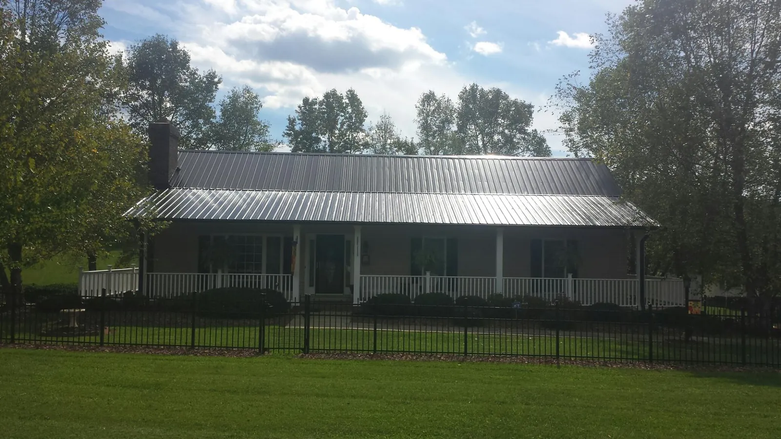 Gray metal roof on a brick ranch with a full width front porch — Gutter Guard Installation work by our crew in Cochecton