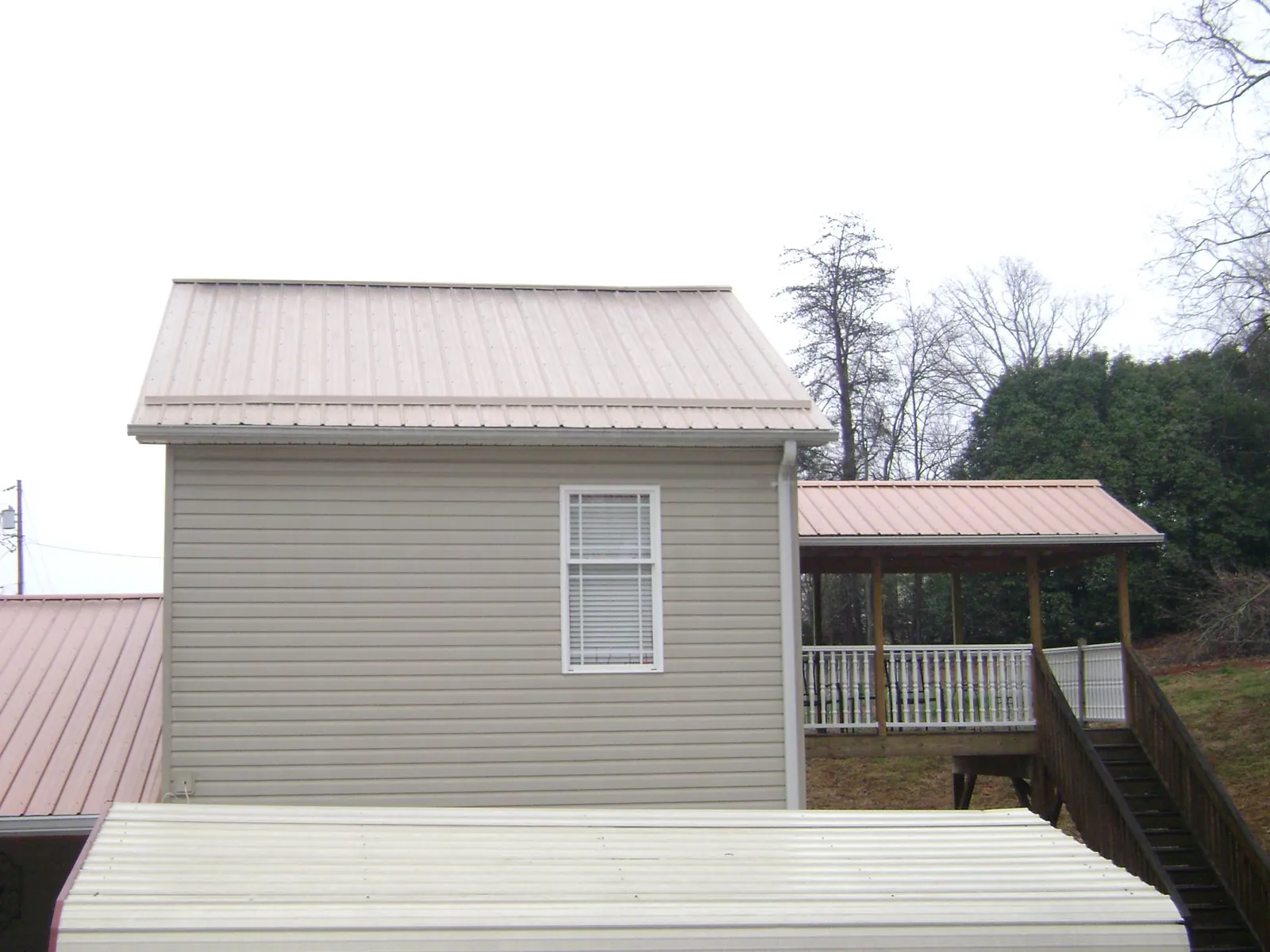 Tan metal roofs on a two story addition and attached porch, from a Roof Replacement job in Cochecton