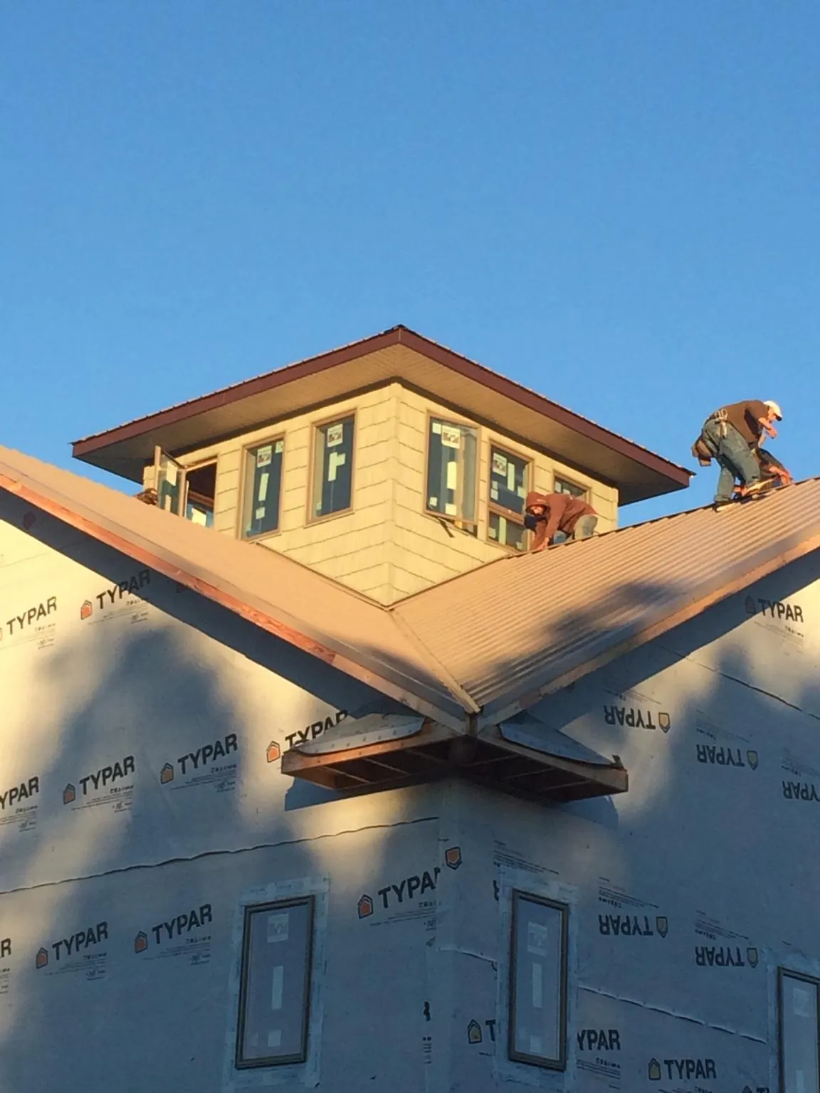 Roofers working around a rooftop cupola on a new metal roof at sunset — Roof Waterproofing in Cochecton by Roofing Brothers